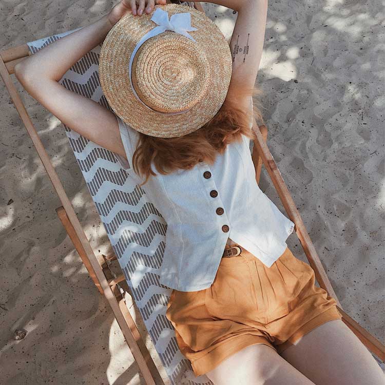 Femme allongée sur un transat avec un chapeau