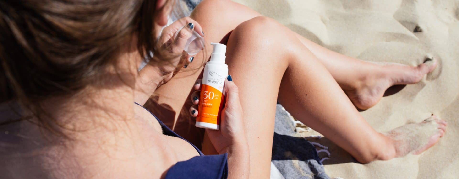 protection solaire dans les mains d'une femme