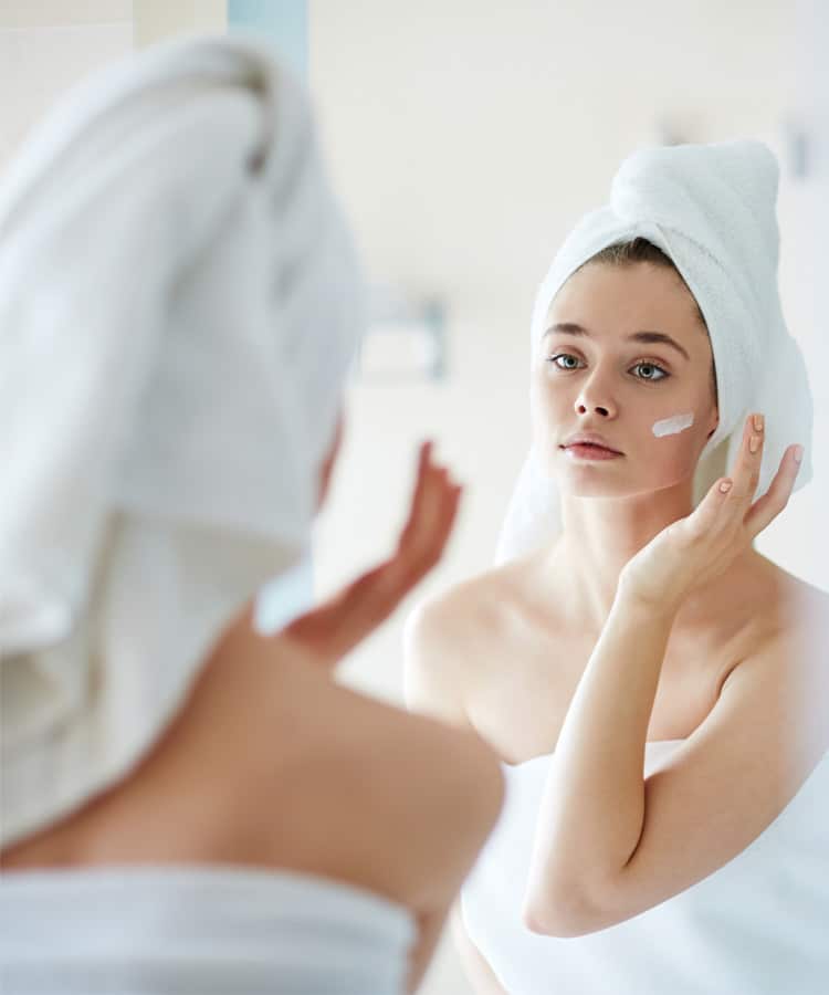 femme qui s'applique de la crème sur le visage