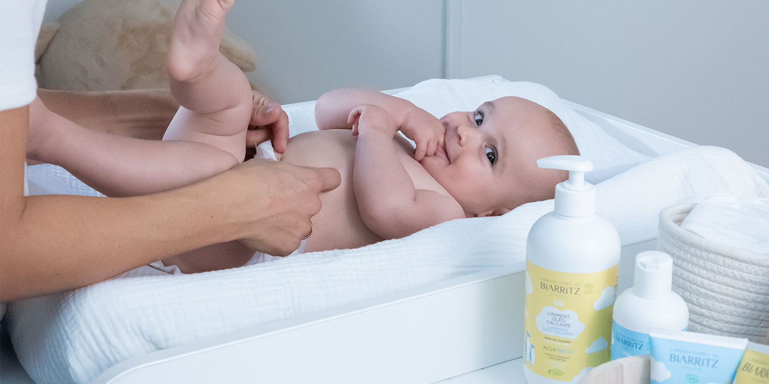 Bébé sur une table à langer avec sa maman qui le change