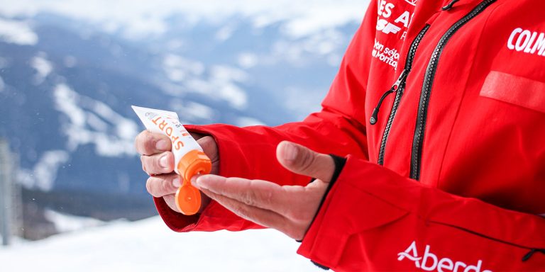 Moniteur de ski qui se met de la crème solaire dans la main