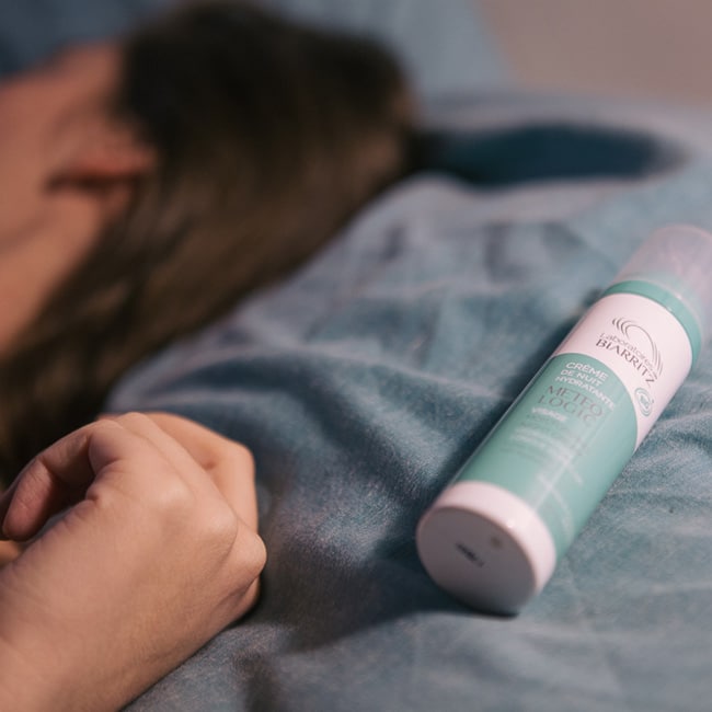 femme qui dort près d'une crème de nuit