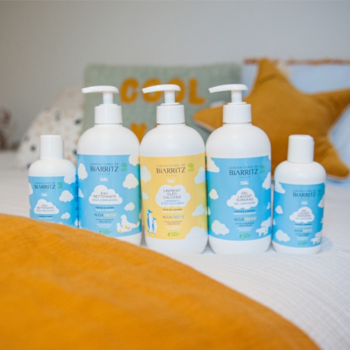 produits de la gamme de soins bébés posés sur un lit