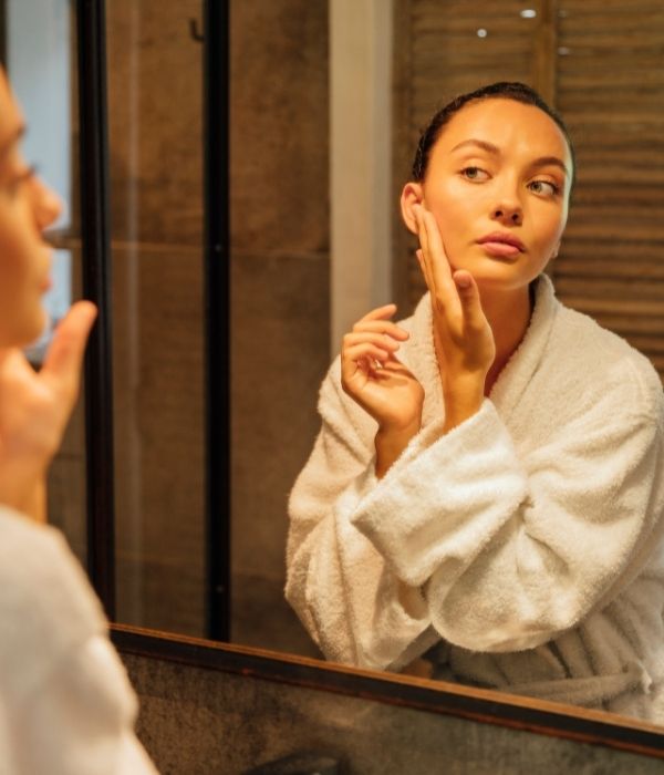 femme qui se regarde et hydrate sa peau