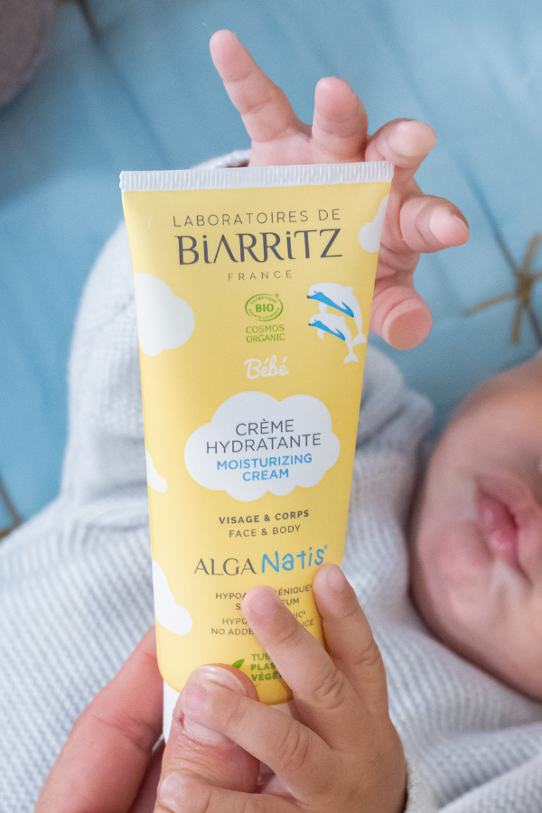 bébé qui attrape un tube de crème hydratante