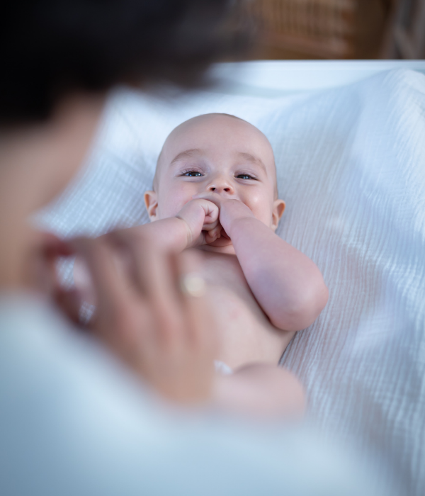 bébé allongé sur le dos qui regarde l'objectif en riant