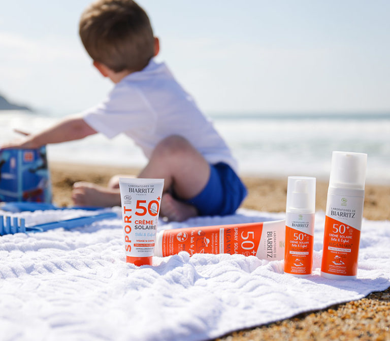 enfant sur la plage avec des crèmes solaires