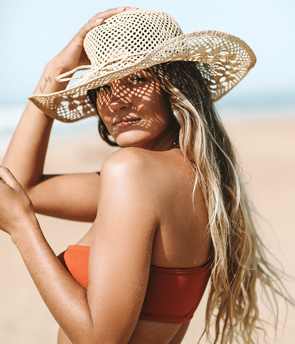 femme avec un chapeau au soleil sur la plage