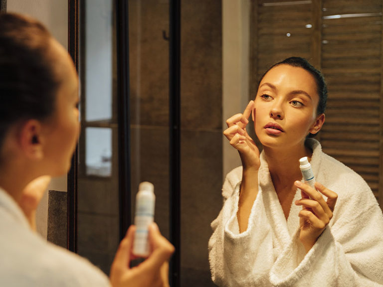 femme qui s'applique de la crème sur le visage