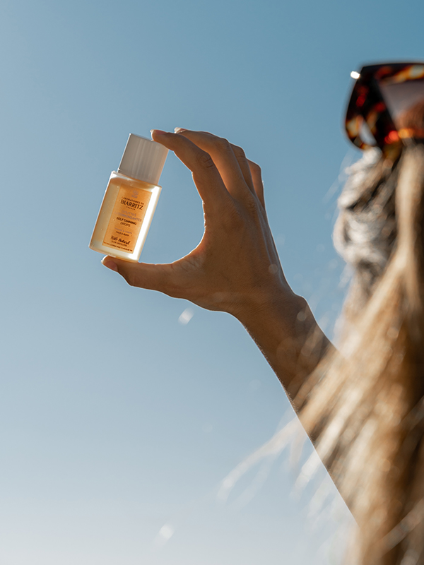 femme qui tient dans sa main les gouttes auto-bronzantes des Laboratoires de Biarritz