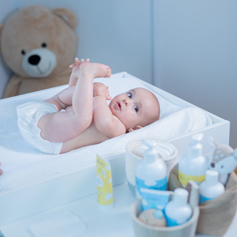 Bébé sur une table à langer avec sa maman qui le change